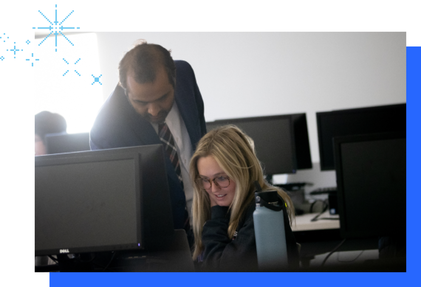 A male KU professor is leaning over a student working on a computer.