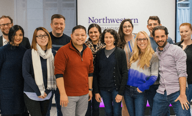 Smiling cohort of students in front of Northwestern sign