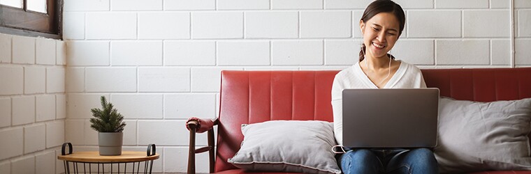 Young professional sits at home on sofa while working on laptop computer