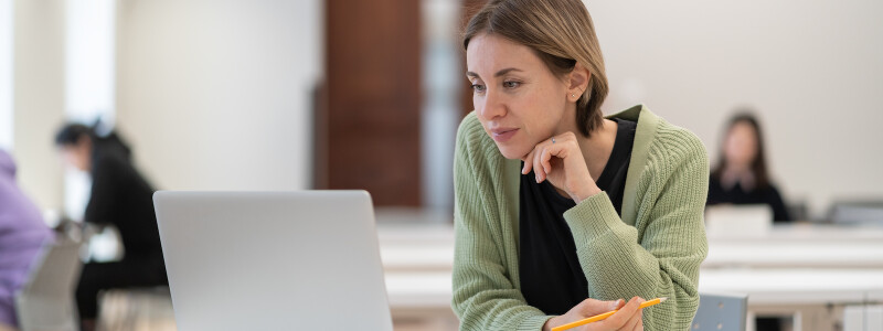 Student older than 30 works on a laptop in a library