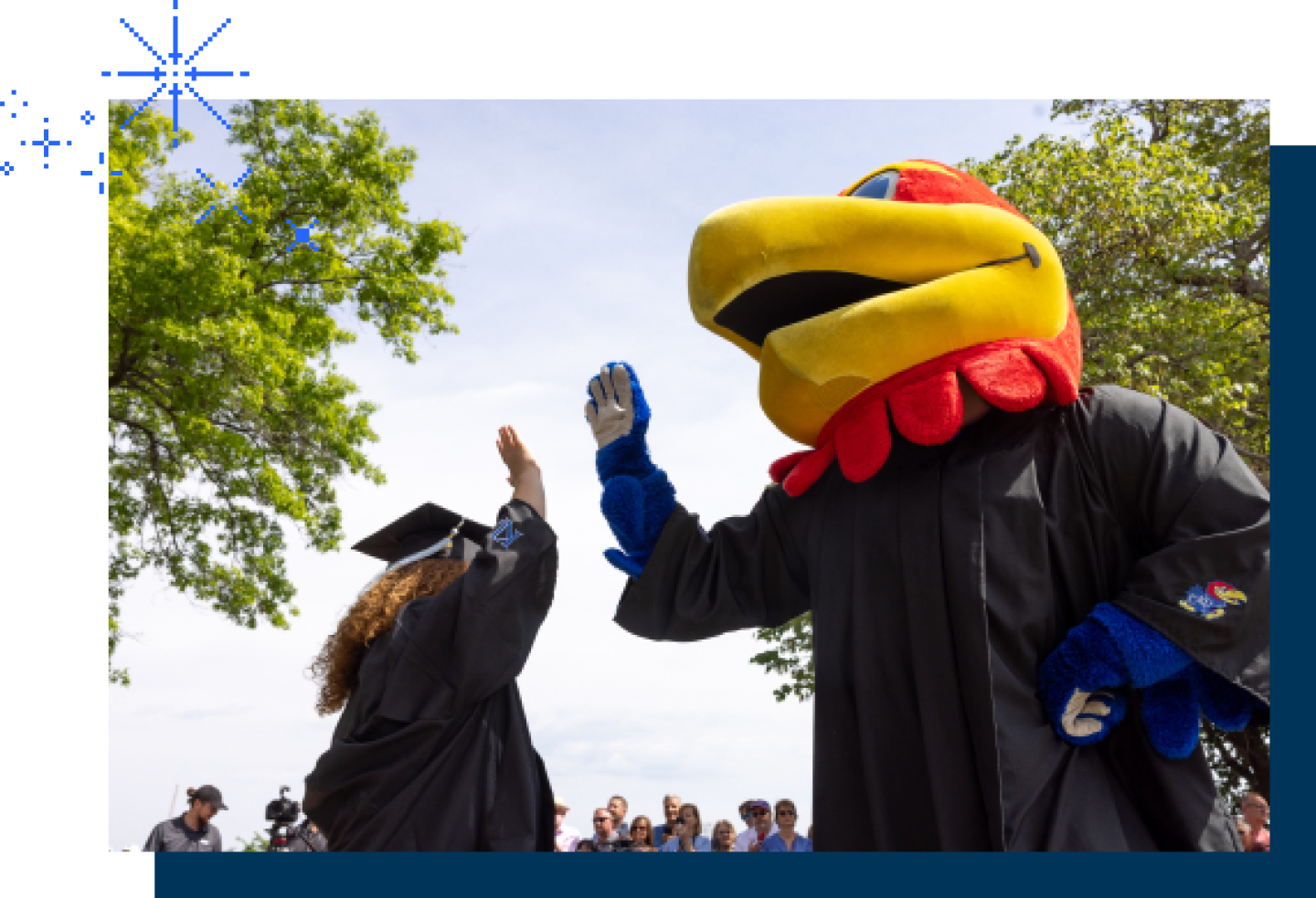 The KU Jayhawk mascot high-fives with a female KU graduate.