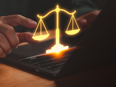 Businessman using laptop with glowing golden scales, symbolizing weighing a decision