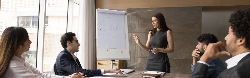 A diverse business team and a female project leader discussing work strategy at a meeting table.
