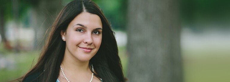 smiling woman with long black hair wearing pearl necklace with matching earrings