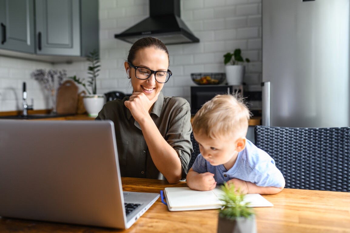Mom at laptop sitting next to young son