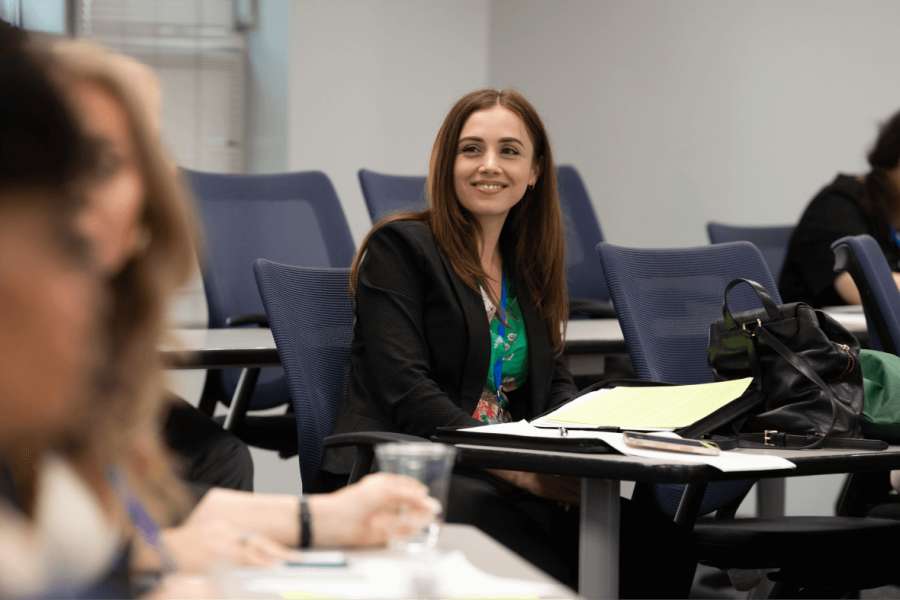 Woman in blazer seated in audience of seminar