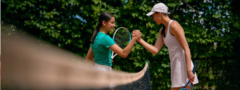 Two women tennis players shake hands over the net