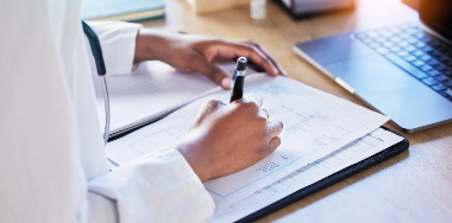 person with a pen and laptop filling in paperwork