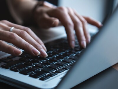 Close up of a woman's hands typing on a laptop