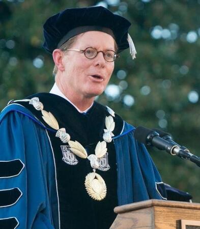 Man in cap and gown speaking at commencement