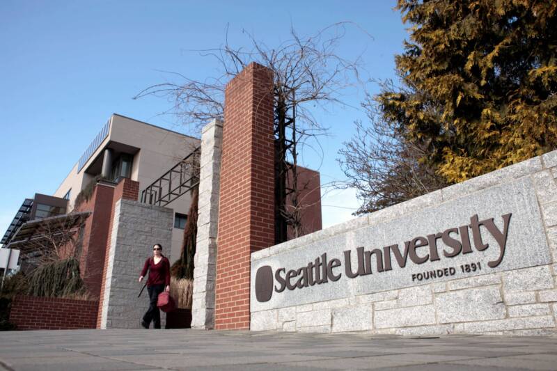Student walking through entrance to Seattle University's campus