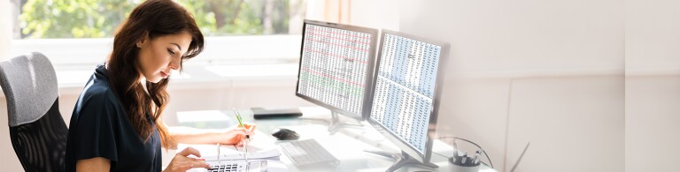 woman-using-calculator-and-computer-at-desk