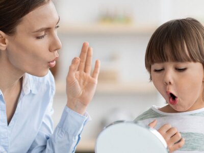 Little boy pronouncing sound O looking at mirror, professional woman therapist teaching kid right pronunciation.