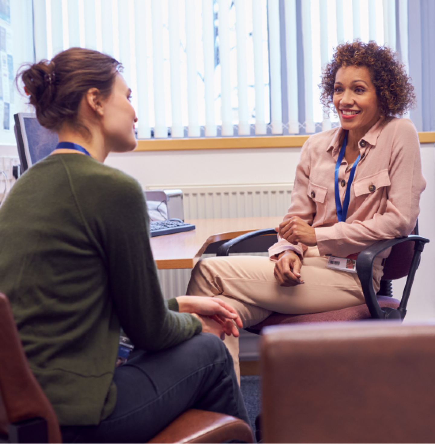 Counselors in lanyard speaking to each other in an office