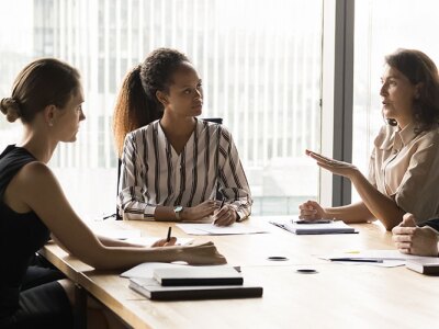 A diverse group of professionals engaged in a discussion around a conference table, representing a collaborative conversation about business ethics and responsible decision-making.