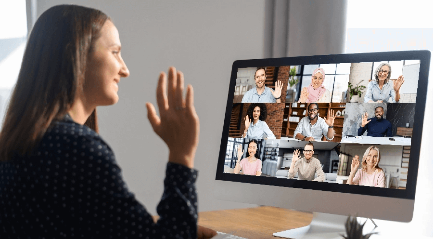 Woman learning remotely waving to classmates on desktop screen