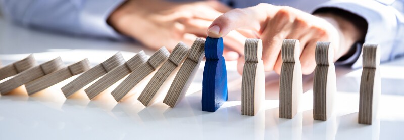 Businessperson stopping falling block on desk
