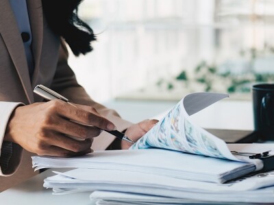 Accountant working on large pile of documents at her desk.