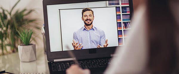 Image of a smiling, bearded man on a laptop screen