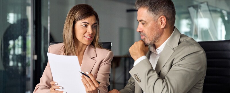 Man and women in business dress looking at documents together.