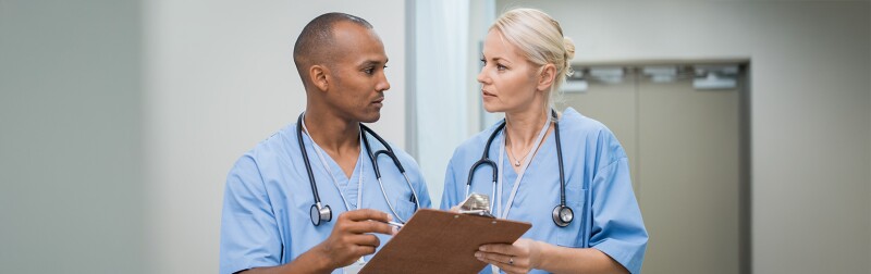 Two nurses discussing patient care; the head nurse is giving guidance