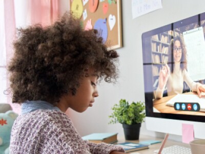 Elementary student sitting at her home computer attending class online