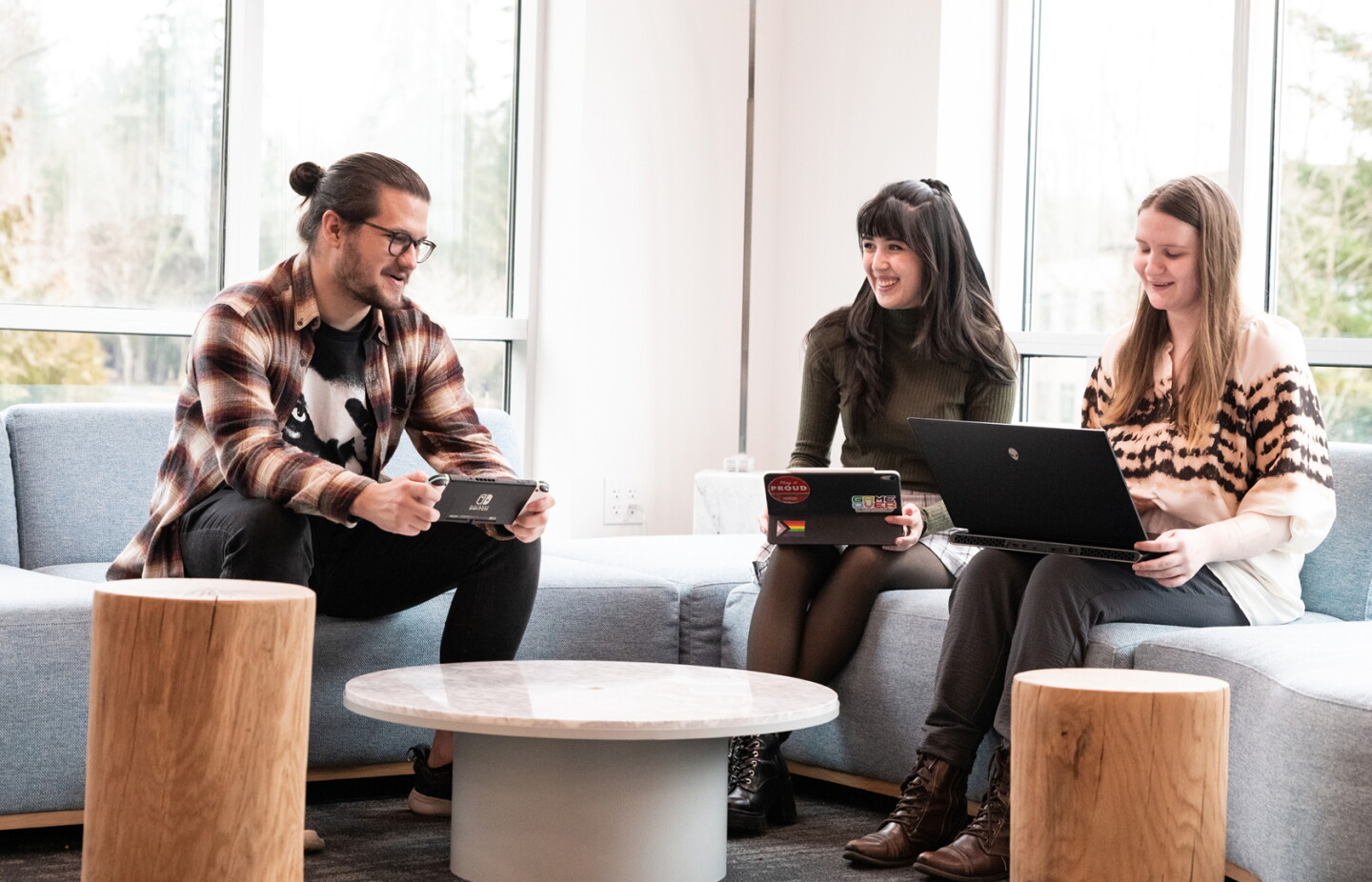 Three students sitting together in a lounge area, collaborating.