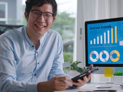 Portrait head shot of young attractive asian man reviewing finance data on computer.