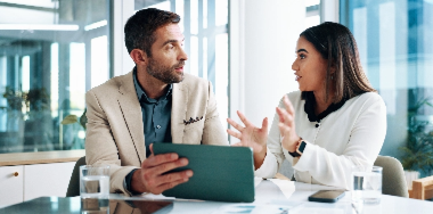 man and woman having a conversation in an office with a large window