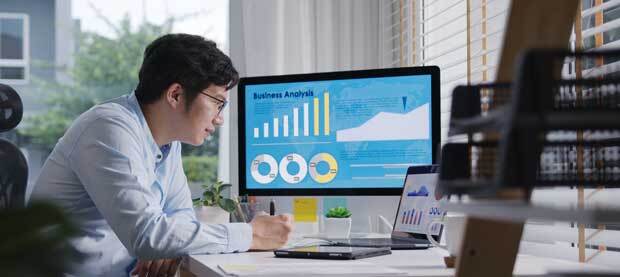 man looking at computer screen of graphs