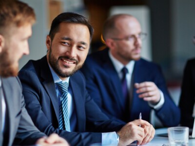 three-man-and-a-woman-smiling-in-suits-talking-bottle-on-table-red-flag