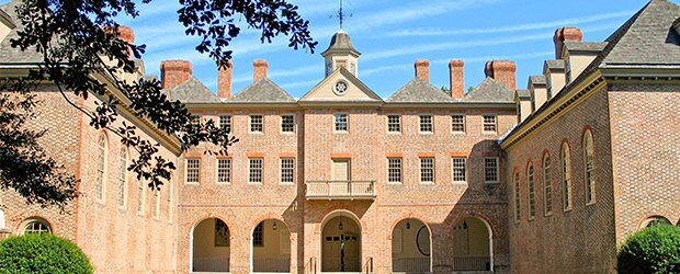 front-head-on-view-of-brick-building-with-blue-sky-and-streak-clouds-and-black-tree-branches-on-left