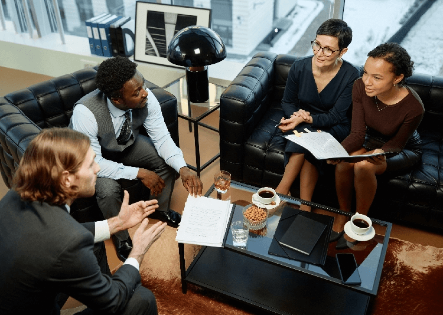 Group of students in business clothing seated around table comparing notes