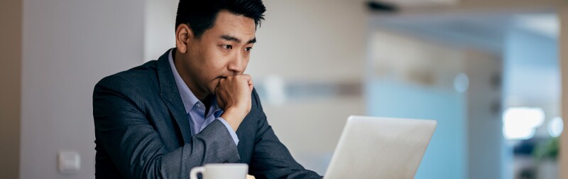Businessman sitting at workplace desk near laptop thinking about a decision