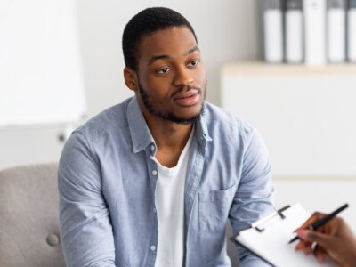 A young black man having session with professional psychologist at mental health clinic.