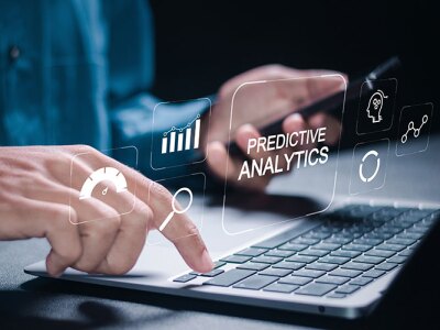 person holding cell phone and typing on laptop displaying predictive analytics icons