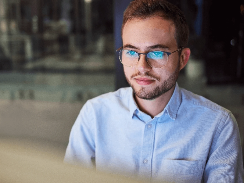 male in buttoned up shirt sitting at a workstation on laptop
