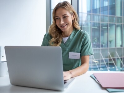 Nurse in scrubs working on her laptop