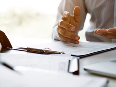 close up image of two sets of hands over paperwork and a laptop