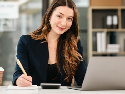 Woman with a laptop, calculator and coffee taking notes