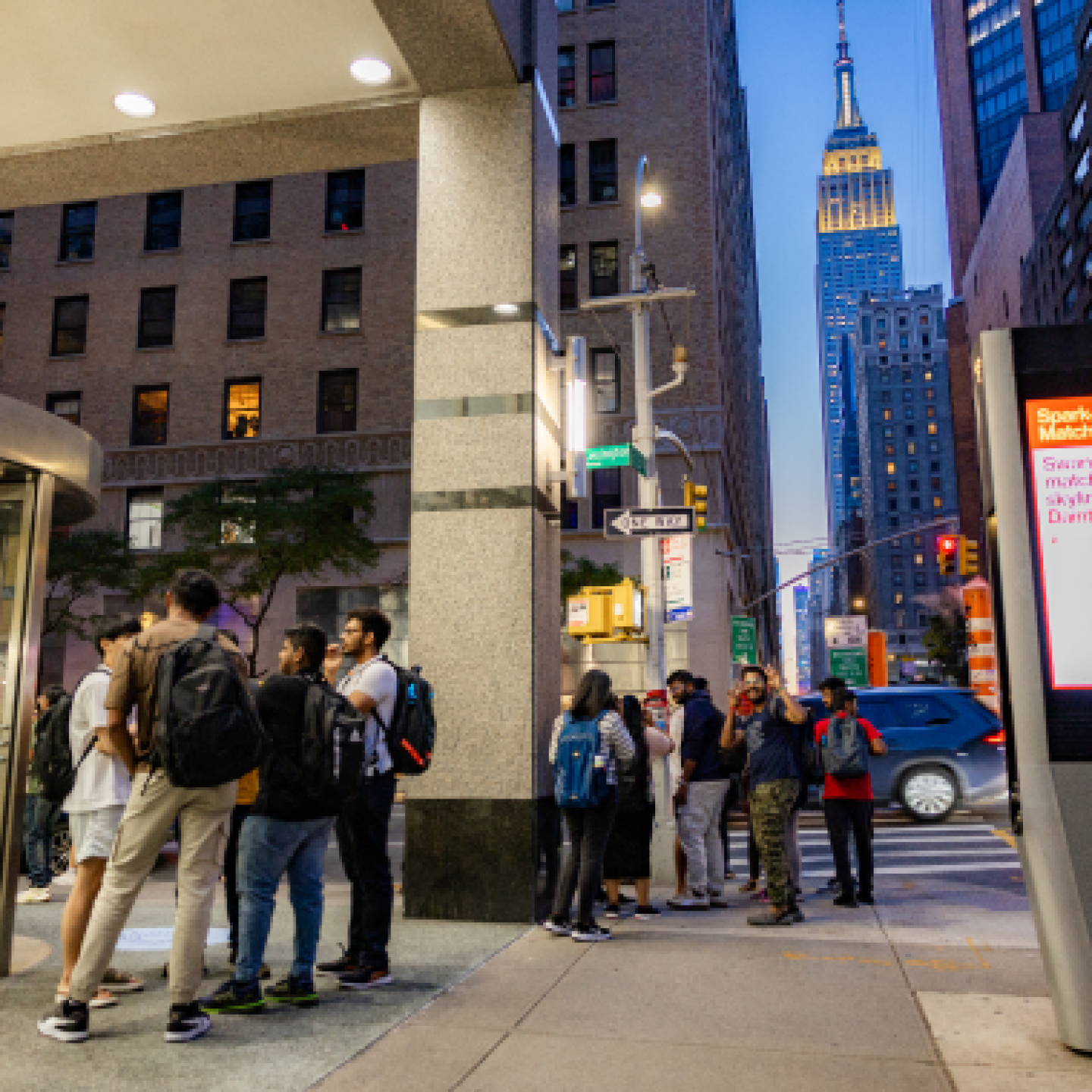 A group of Yeshiva University students gathers on a sidewalk in downtown New York City.