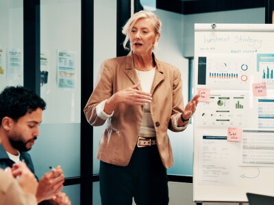 A business professional presents data and charts to colleagues during a strategy meeting.