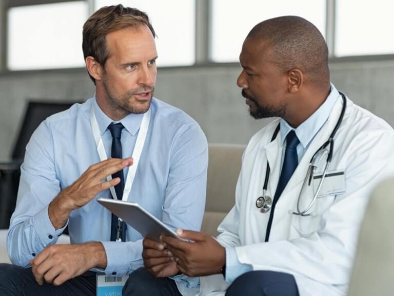 Healthcare compliance officer speaking with doctor holding a tablet