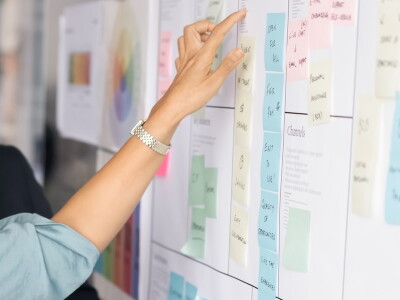 Project managers working on tasking at Kanban scrum board, discussing teamwork strategy