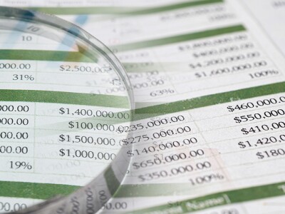 Magnifying glass examining spreadsheets