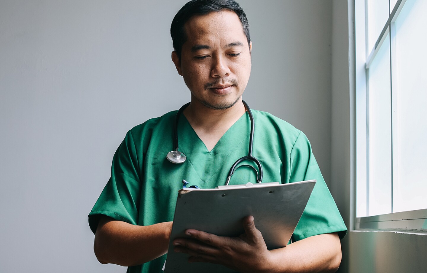 Male nurse writing on a clipboard