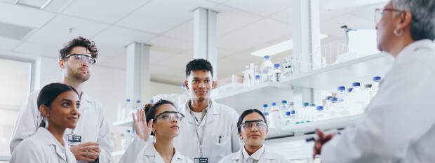 A diverse group of clinical researchers in lab listening during a discussion