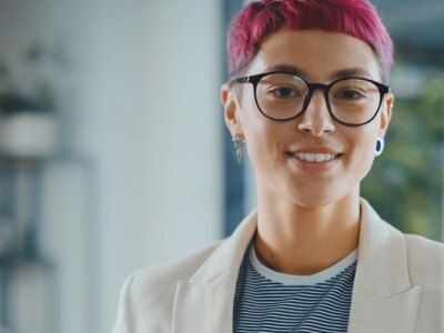 Person with dyed hair and glasses in casual business attire