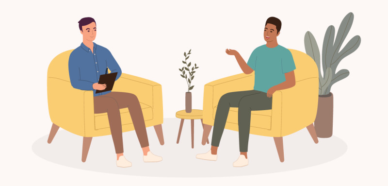 Psychologist taking notes while listening to his smiling male client