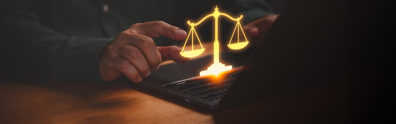 Businessman using laptop with glowing golden scales, symbolizing weighing a decision